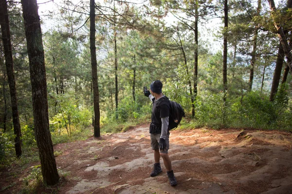 Sırt çantalı turist dağlarda akıllı telefonuyla fotoğraf çekiyor.