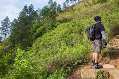 Sırt çantalı bir adam dağlarda tek başına seyahat ediyor.