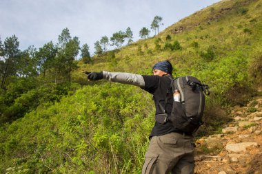 Sırt çantalı bir adam dağlarda tek başına seyahat ediyor.