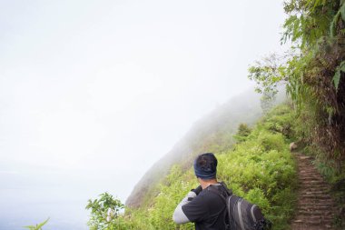 Sırt çantalı bir adam dağlarda tek başına seyahat ediyor.