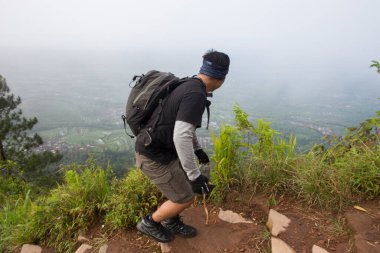 Sırt çantalı bir adam dağlarda tek başına seyahat ediyor.