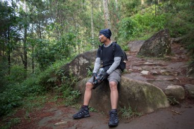 Yürüyüş yapan adam dağlarda yürüdükten sonra şişeden su içiyor ve dinleniyor. 