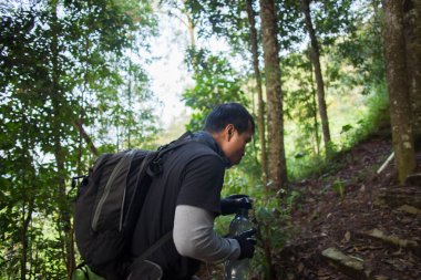 Yürüyüş yapan adam dağlarda yürüdükten sonra şişeden su içiyor ve dinleniyor. 