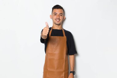 Yakışıklı önlüklü adam mutlu bir şekilde gülümsüyor.