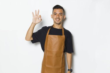 Yakışıklı önlüklü adam mutlu bir şekilde gülümsüyor.