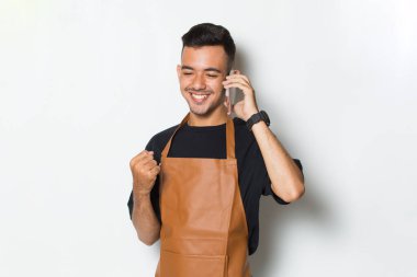 Neşeli genç adam barmen ya da garson beyaz arka planda izole cep telefonu kullanıyor.