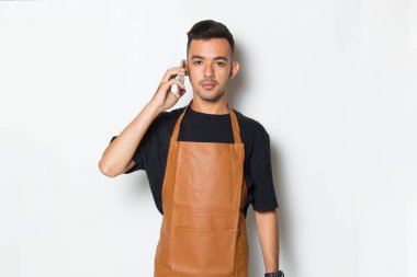 Neşeli genç adam barmen ya da garson beyaz arka planda izole cep telefonu kullanıyor.