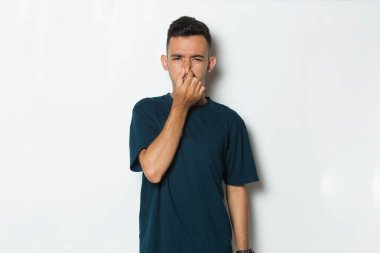 Burnunu kötü bir koku yüzünden tutan bir adam.