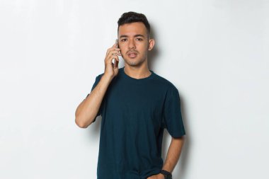 Şaşırmış genç adam beyaz arka planda izole cep telefonu kullanıyor.