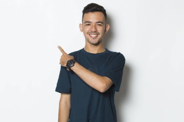 Genç yakışıklı adam beyaz arka planda izole edilmiş boş alanı işaret ediyor.