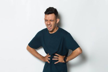 Hasta bir adamın beyaz arka planda karnı ağrıyor.