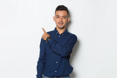 Genç yakışıklı iş adamı beyaz arka planda izole edilmiş boş alanı işaret ediyor.