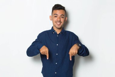 Genç yakışıklı iş adamı beyaz arka planda izole edilmiş boş alanı işaret ediyor.