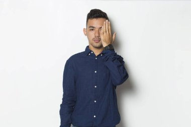 Genç ve yakışıklı bir iş adamı beyaz arka planda tek gözünü kapatıyor.