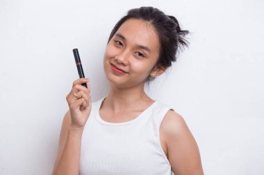 Güzel genç Asyalı kadın beyaz arka planda izole edilmiş ruj kullanıyor.