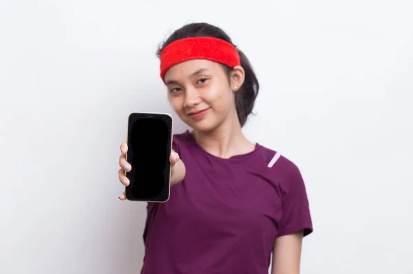 年轻的亚洲女运动员在白色背景下展示手机 — 图库照片