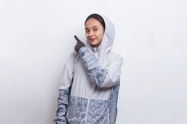 Young asian hiker woman with backpack pointing finger on empty space on white background