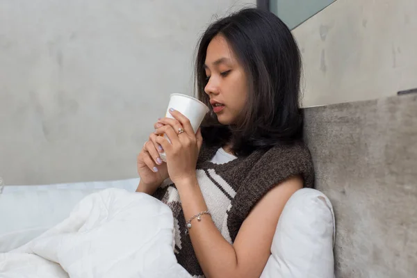 sick young asian beautiful woman drinking water in bed