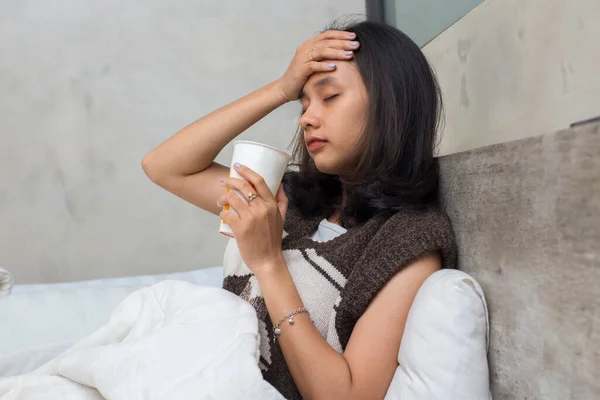 sick young asian beautiful woman drinking water in bed