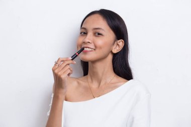 Güzel genç Asyalı kadın beyaz arka planda izole edilmiş ruj kullanıyor.