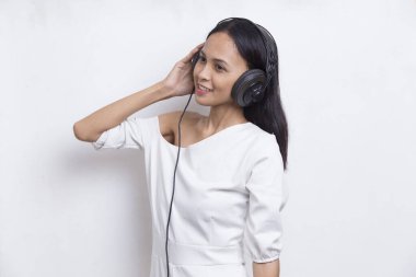 Güzel, genç Asyalı bir kadın beyaz arka planda izole edilmiş müzik dinliyor.