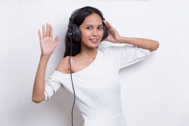 Güzel, genç Asyalı bir kadın beyaz arka planda izole edilmiş müzik dinliyor.