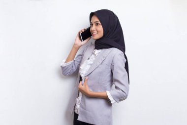 Mutlu genç Asyalı güzel Müslüman kadın beyaz arka planda izole edilmiş cep telefonu kullanıyor.