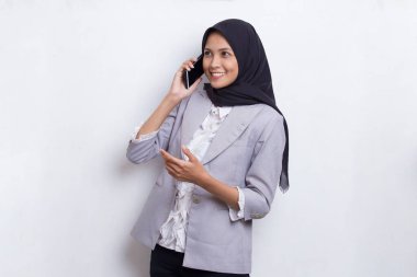 Mutlu genç Asyalı güzel Müslüman kadın beyaz arka planda izole edilmiş cep telefonu kullanıyor.