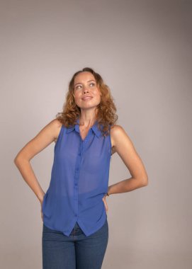 Kıvırcık saçlı sarışın kız stüdyoda poz veriyor.