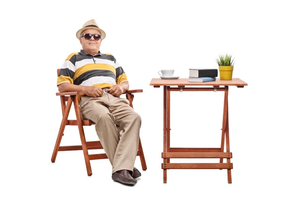 Cavalheiro sênior alegre sentado em uma mesa — Fotografia de Stock