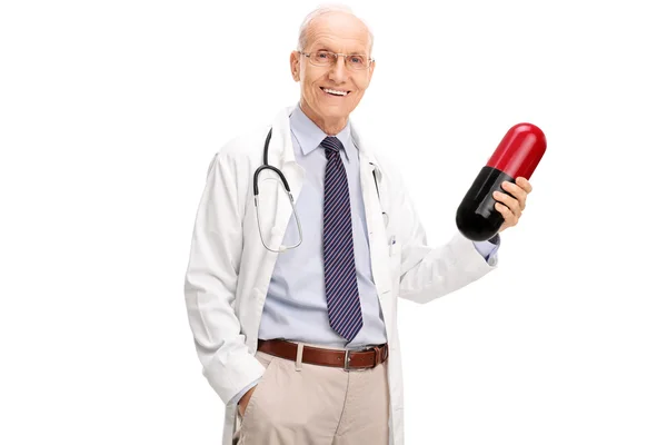 Mature doctor holding a large pill — Stock Photo, Image