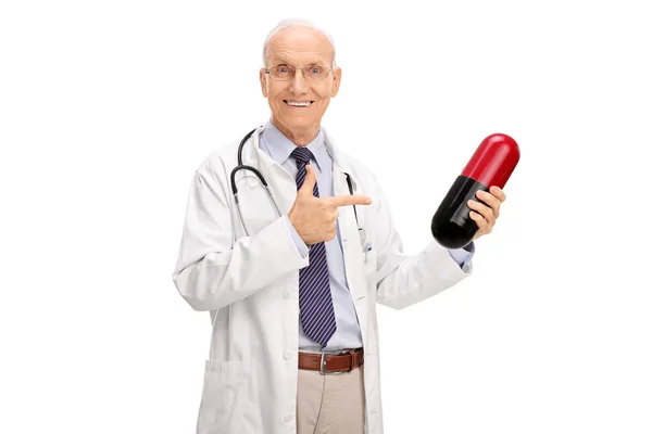 Mature doctor holding a huge pill — Stock Photo, Image