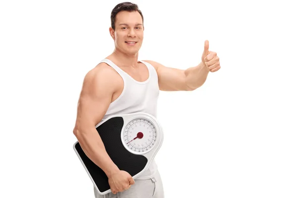 Ο τύπος κρατώντας μια κλίμακα βάρους και εγκατάλειψη του αντίχειρα — Φωτογραφία Αρχείου