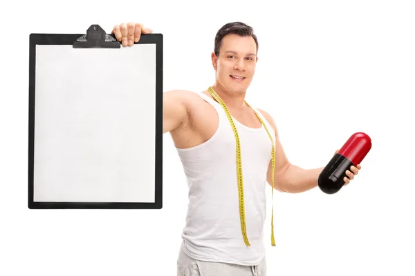 Man holding a diet pill and a clipboard — Stock Photo, Image