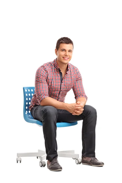 Jovem homem alegre sentado em uma cadeira — Fotografia de Stock