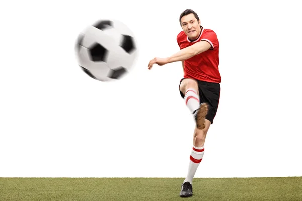 Футболист пинает мяч по траве — стоковое фото