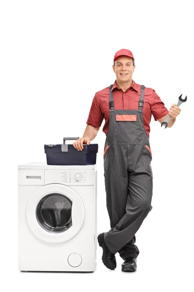 Repairman holding a wrench next to a washing machine — Stock Photo, Image