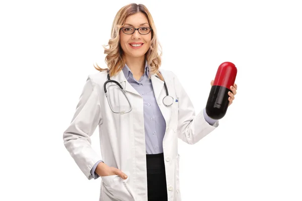 Médico fêmea segurando uma pílula grande — Fotografia de Stock