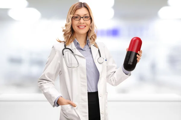 Doctora sosteniendo una píldora enorme — Foto de Stock