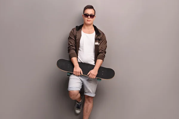 Jonge mannelijke schaatser houden een skateboard — Stockfoto