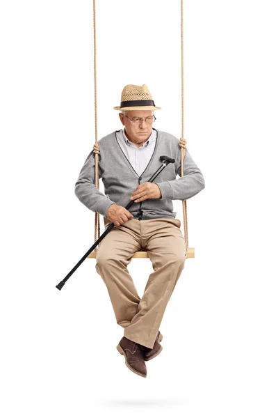 Senior man with cane and sitting on a swing — Stock Photo, Image