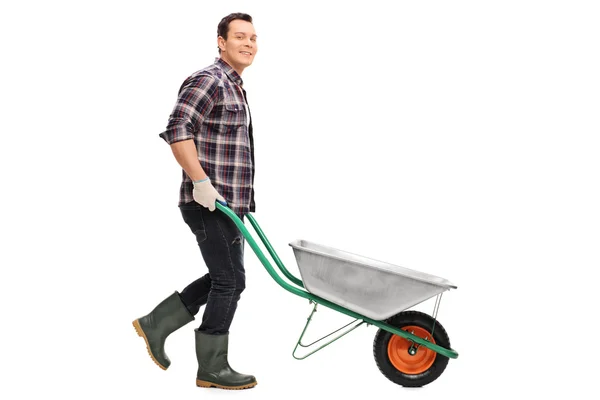 Jardineiro empurrando um carrinho de mão vazio — Fotografia de Stock