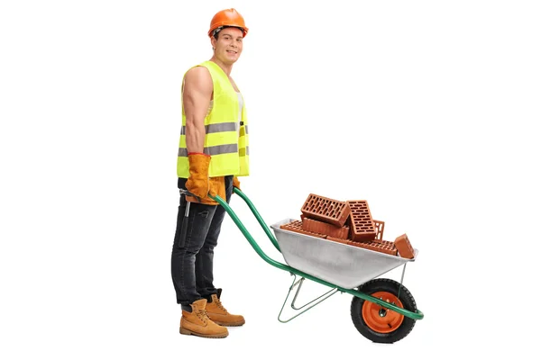 Worker posing with a wheelbarrow full of bricks — Stock Photo, Image