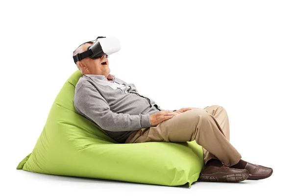 Sénior usando um fone de ouvido VR sentado em saco de feijão — Fotografia de Stock