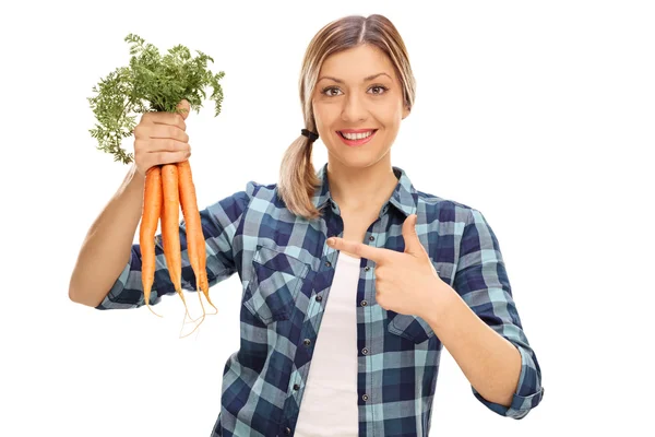 Mujer alegre sosteniendo un montón de zanahorias — Foto de Stock