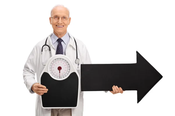 Doctor holding a weight scale and arrow — Stock Photo, Image