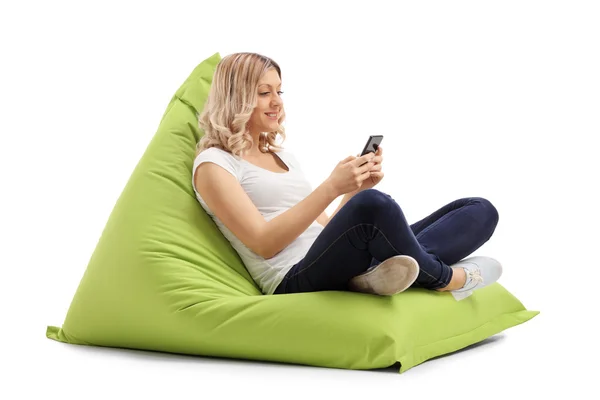 Woman texting on phone seated on beanbag — Stock Photo, Image