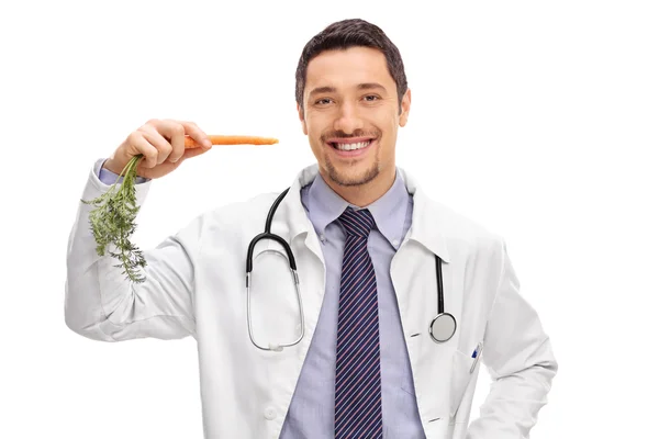 Young cheerful doctor holding a carrot — Stock Photo, Image