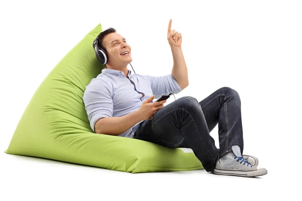 Guy listening to music seated on beanbag — Stock Photo, Image