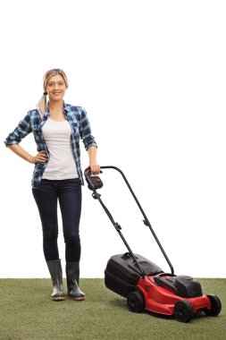 Genç kadın bir çim biçme makinesi ile poz 
